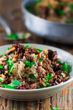 a close up of a bowl of food with rice and meat in it on a wooden table