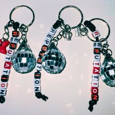 three disco ball keychains with the words london on them hanging from each other