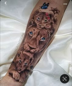 a tattoo with lions and butterflies on it's arm, which has blue eyes