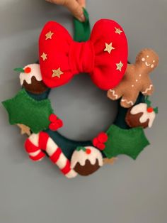 a hand holding a christmas wreath with gingerbreads and holly