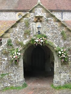 an old stone building with flowers growing out of it