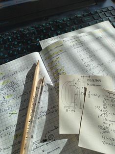 some papers are laying on top of a computer keyboard and next to a pencil, ruler, and calculator