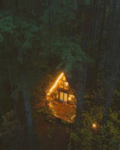 a cabin nestled in the woods at night with lights on it's roof and windows