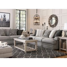 a living room filled with furniture and a chandelier hanging above the couches