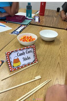 candy corn sticks are sitting on a table next to a bowl of candies and a sign that says candy corn sticks