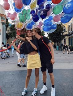 two people kissing while holding balloons in the air