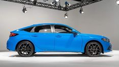 a bright blue sports utility vehicle parked in a showroom with spotlights on the ceiling