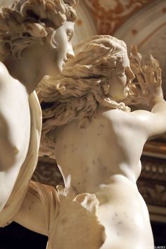 two white marble statues with one holding the other's head in front of him