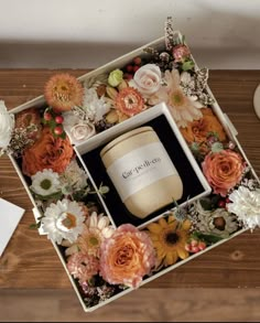 an open box containing a candle surrounded by flowers