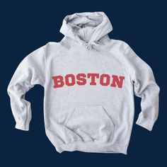 "Boston-In-Red-Lettering Classic Hoodie | Color: Sport Grey Embrace the spirit of the city with our \"Boston Classic\" Sports Grey Hoodie. This hoodie combines comfort, style, and a touch of city pride, making it a must-have for both locals and Boston enthusiasts alike. Features: Color & Design: A sleek sports grey base provides the perfect canvas for the standout feature - \"BOSTON\" emblazoned across the front in bold, red letters. The vibrant red against the muted grey creates an eye-catching contrast that's sure to turn heads. Material: Crafted from a premium blend of cotton and polyester, this hoodie promises both warmth and breathability. It's perfect for those chilly days or a casual evening stroll through the city. Fit & Comfort: Designed with a unisex fit, it suits all body types. Hooded College Sweatshirt With Double-lined Hood, College Hooded Sweatshirt With Double-lined Hood, Double-lined Hooded Sweatshirt For College, School Spirit Sweatshirt With Lettering For Streetwear, Varsity Hoodie For College In Winter, Fall Fan Gear Hoodie With Graphic Print, Varsity Winter Hoodie For College, Fall Graphic Print Hoodie For Fan Gear, Cotton Hoodie For Fan Gear