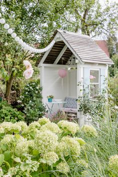 a garden shed with flowers in the foreground