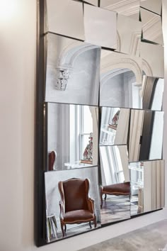 a large mirror reflecting the interior of a room with chairs and mirrors on the wall