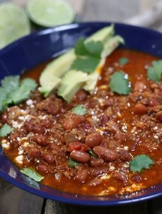 a blue bowl filled with chili and beans