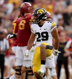 a football player is running on the field with his foot in the air and other players behind him