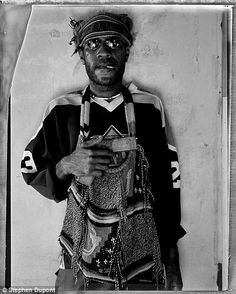 a black and white photo of a man wearing an old fashioned hat with chains around his neck