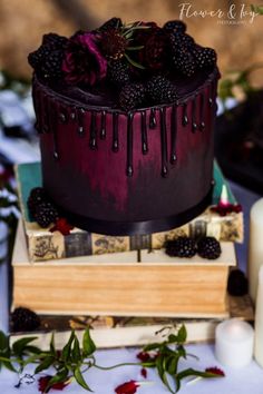 a chocolate cake with blackberries and roses on top is sitting next to some candles