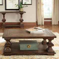 a coffee table with some books on top of it in a living room next to two framed pictures