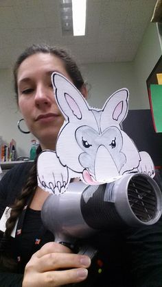 a woman holding up a blow dryer with a drawing of a bunny on it