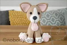 a crocheted dog sitting on top of a wooden table next to a pillow