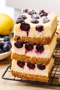 three slices of cake with blueberries and lemons on the side sitting on a cooling rack