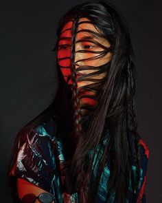 a woman's face is covered in strips of hair and has long black hair