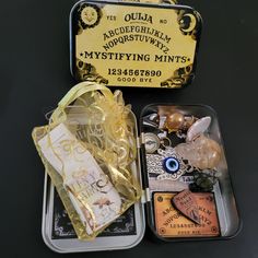 two tins filled with assorted items sitting on top of a black table next to each other