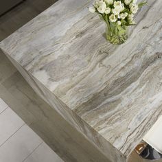 a vase with flowers on top of a marble table