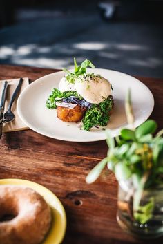 a white plate topped with food on top of a wooden table next to a donut