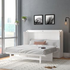 a white bed sitting in a bedroom on top of a wooden floor next to a window