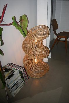 a wicker lamp sitting on top of a table next to a book shelf and chair