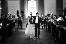 a bride and groom holding sparklers in front of their wedding party at the state house