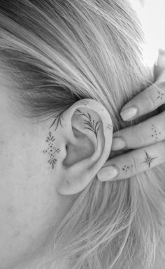 a woman's ear with tattoos on it