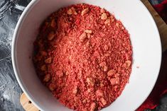 a white bowl filled with red food on top of a wooden cutting board