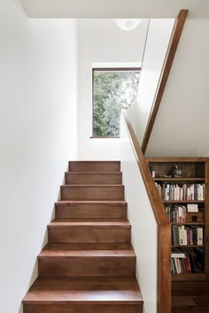 the stairs are made of wood and have bookshelves on each side, along with a window above them