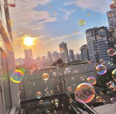 soap bubbles are floating in the air on a balcony overlooking a cityscape at sunset