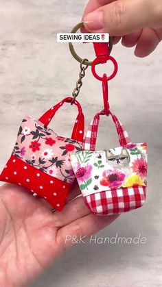 two small purses are being held up by someone's hand with the keychain