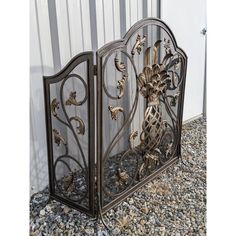 an ornate iron gate is sitting on gravel