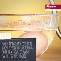 an egg in a glass bowl with a sign on it that says, top tip warm refrigerator eggs up to room temperature by placing them in a bowl of warm water for five minutes