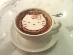 a cup of coffee with a hello kitty drawn on it