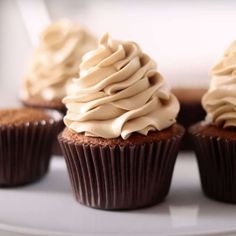 several cupcakes with frosting on a white plate