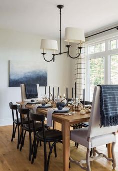 the dining room table is set with black and white chairs, an art work on the wall