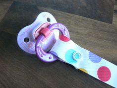 a pacifier sitting on top of a wooden table next to a rubber toy ring