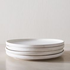 three white plates stacked on top of each other in front of a plain wall background