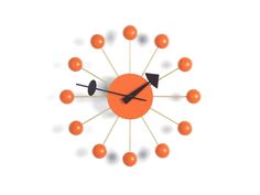 an orange clock with black hands and arrows on the face is surrounded by small balls