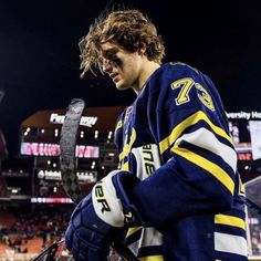 a hockey player is holding a snake in his hand and looking down at the ground