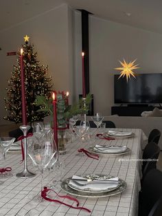 a dining room table set with place settings and christmas tree in the backgroud