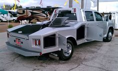 a silver truck parked in front of a trailer with an open hood on it's flatbed