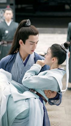 two people dressed in traditional japanese clothing, one is holding the other's head