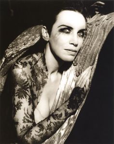 black and white photograph of a woman with her hands on her chest, leaning against the back of a chair