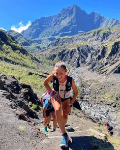 a woman running down a mountain trail in the mountains